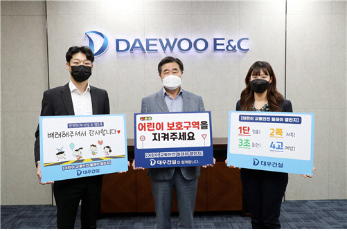 김형(가운데) 대우건설 사장이 어린이 교통안전 릴레이 챌린지 참여의 일환으로 교통안전표어를 들고 기념사진을 찍고 있다.                       <대우건설 제공>